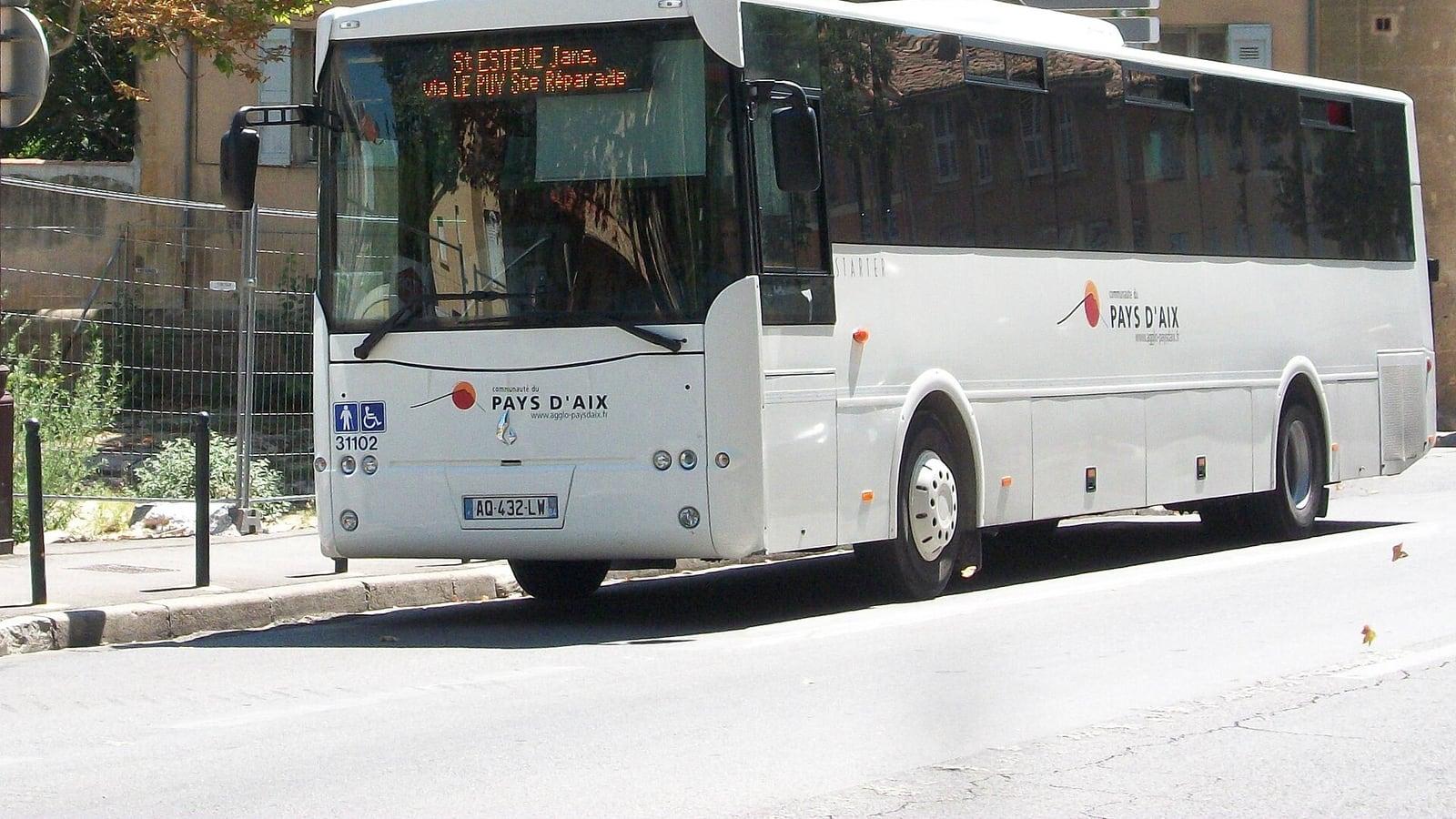 Un autocar blanc aux couleurs de la Communauté du Pays d'Aix stationné le long d'un trottoir, sa girouette annonçant Saint-Estève-Janson via Le Puy-Sainte-Réparade