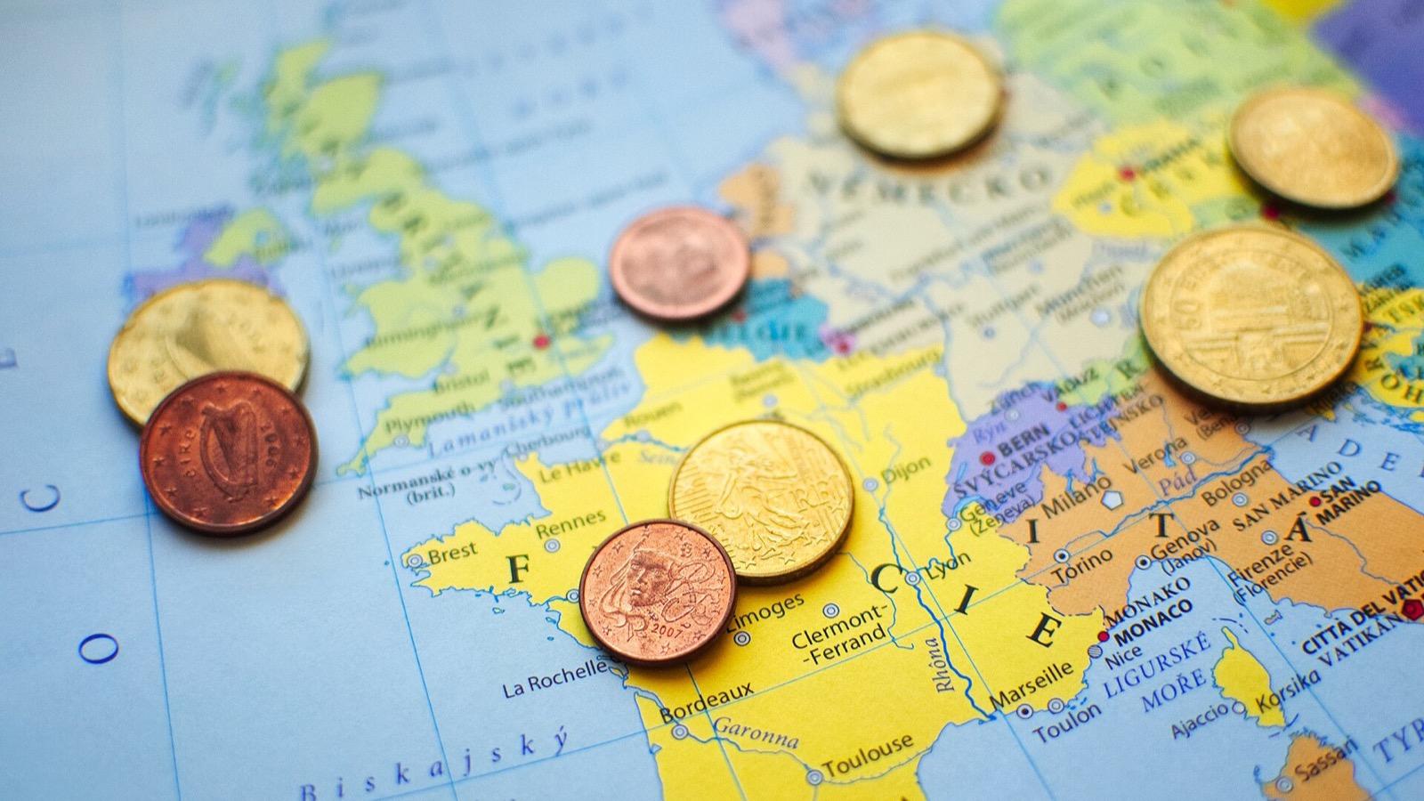 Des pièces de monnaie en euros posées sur une carte de l'Europe