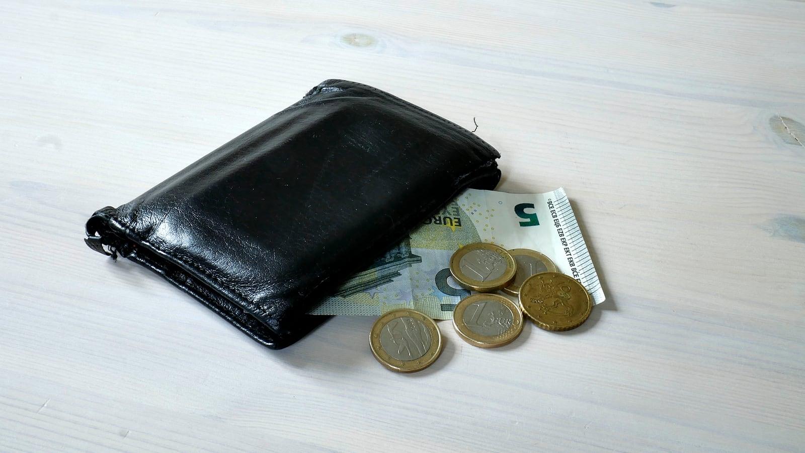 Un portefeuille avec des pièces et un billet de 5 euros