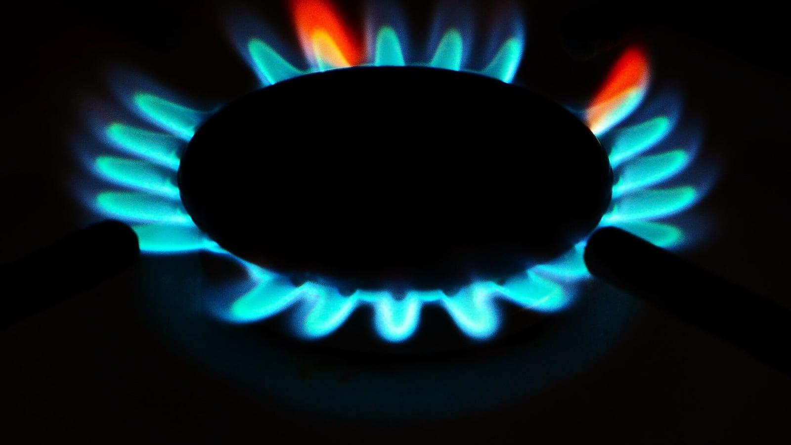 Les flammes bleues d'un brûleur de gazinière allumé, dans la pénombre