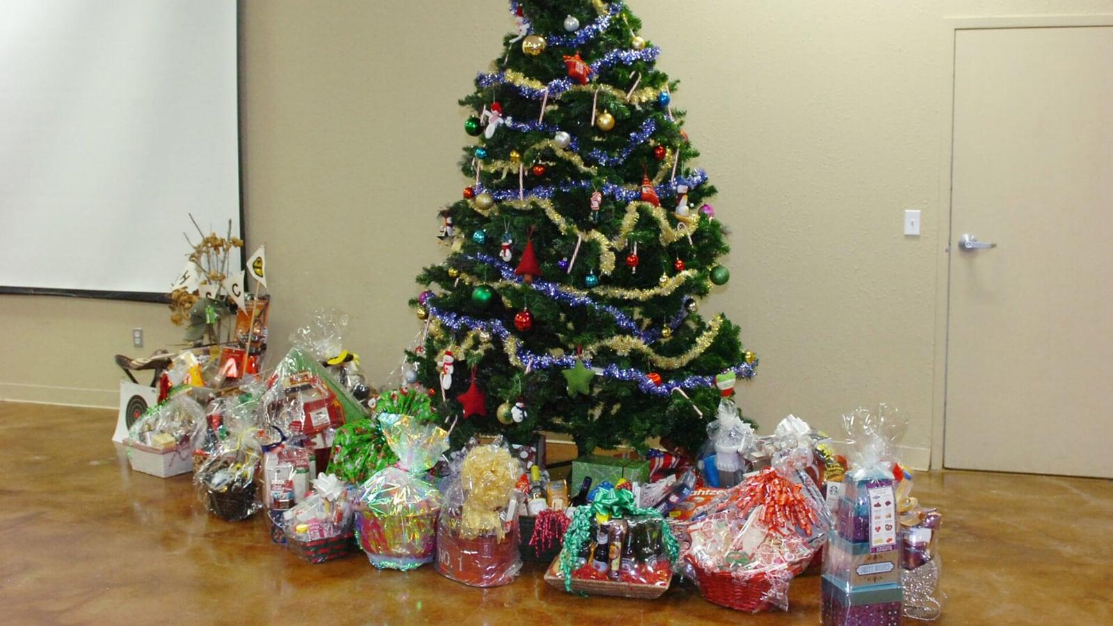 Des paniers garnis emballés de cellophane et de rubans, posés au pied d'un sapin de Noël décoré dans une salle