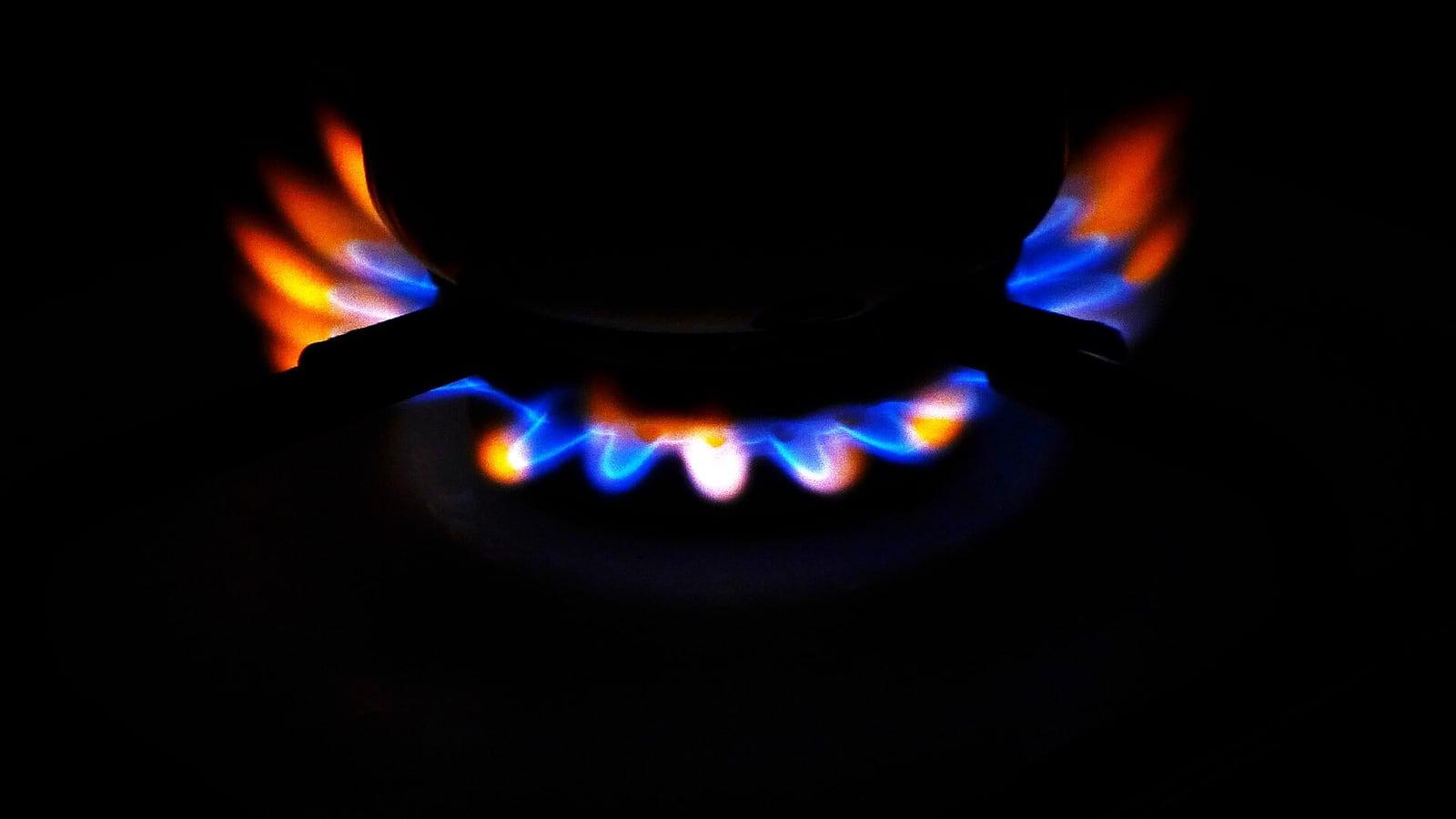 Flammes bleues et orangées d'un brûleur de gazinière allumé, dans l'obscurité