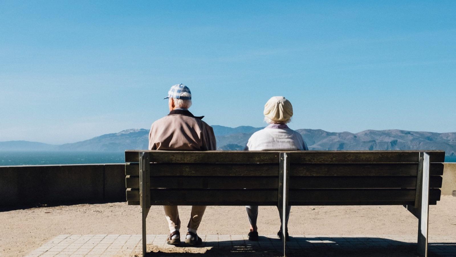 Un couple de personnes âgées assis sur un banc face à la mer