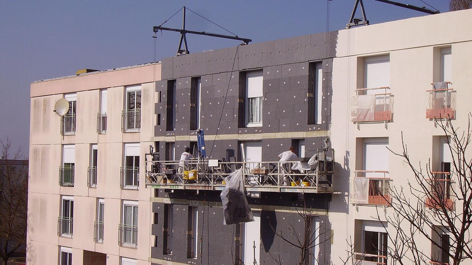 Des ouvriers posent une isolation thermique par l'extérieur sur la façade d'un immeuble