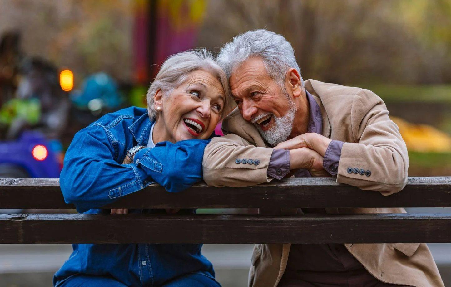 Un couple de personnes âgées souriant sur un banc